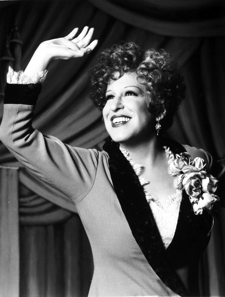 Bette Midler Portrait Waving Her Hand In Grey Linen Deep V-Neck Dress With White Ruffled Collar And Flower Corsage Photo Print (